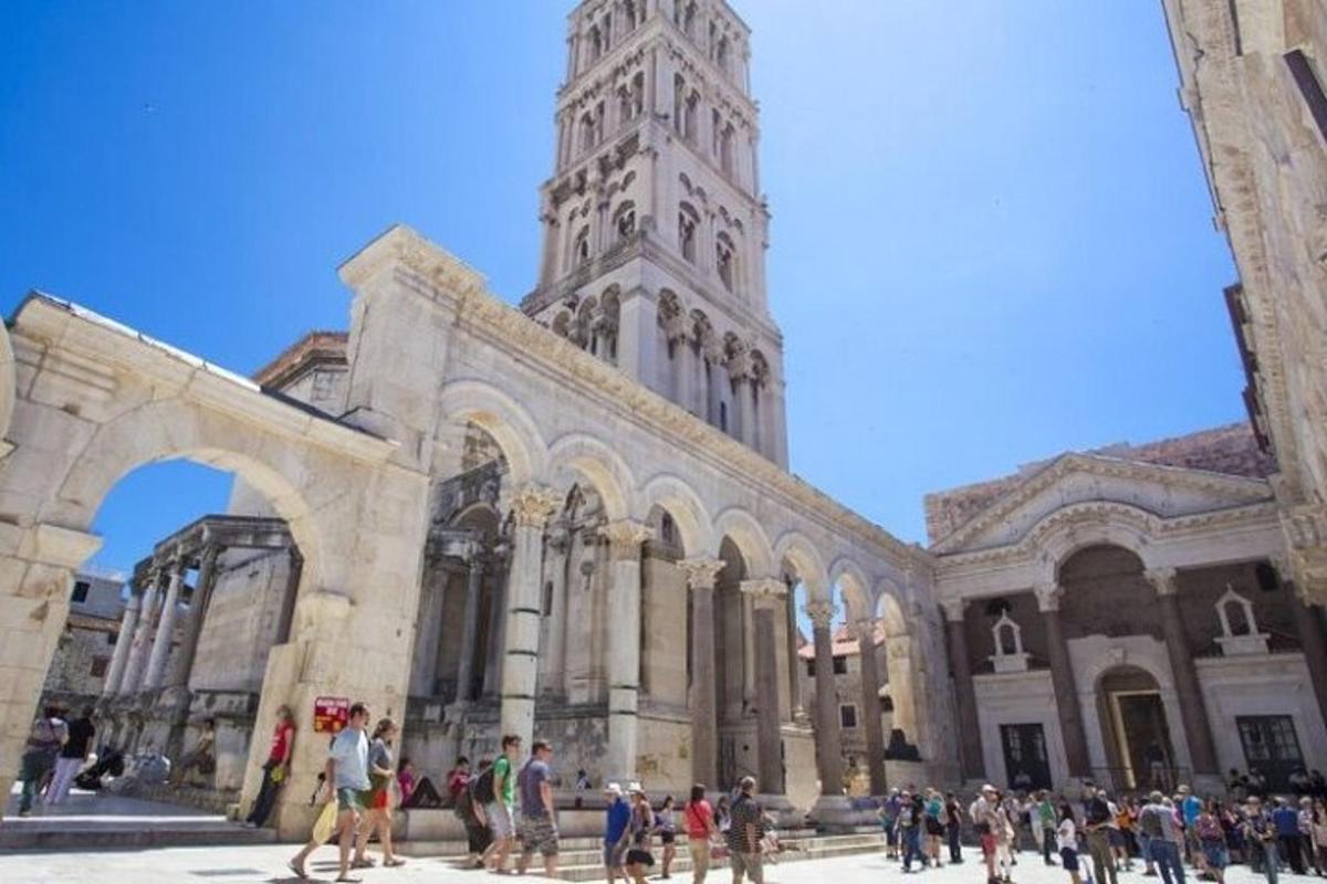 um grupo de pessoas caminhando em frente a um prédio com uma torre de relógio