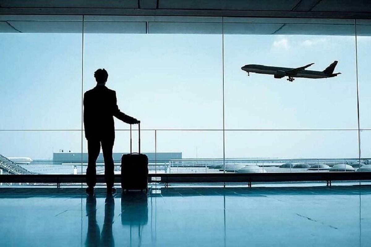 egy férfi áll a repülőtéren, és egy repülőgépet néz