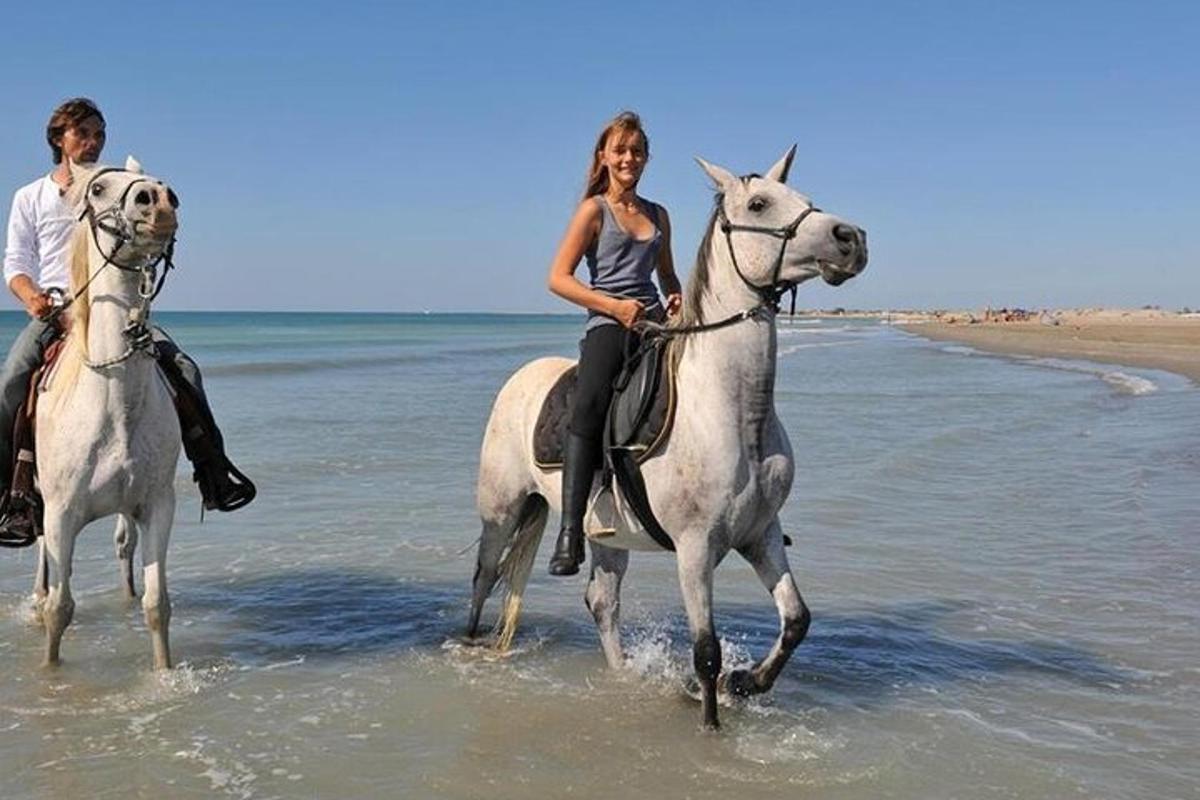 un uomo e una donna a cavallo sulla spiaggia