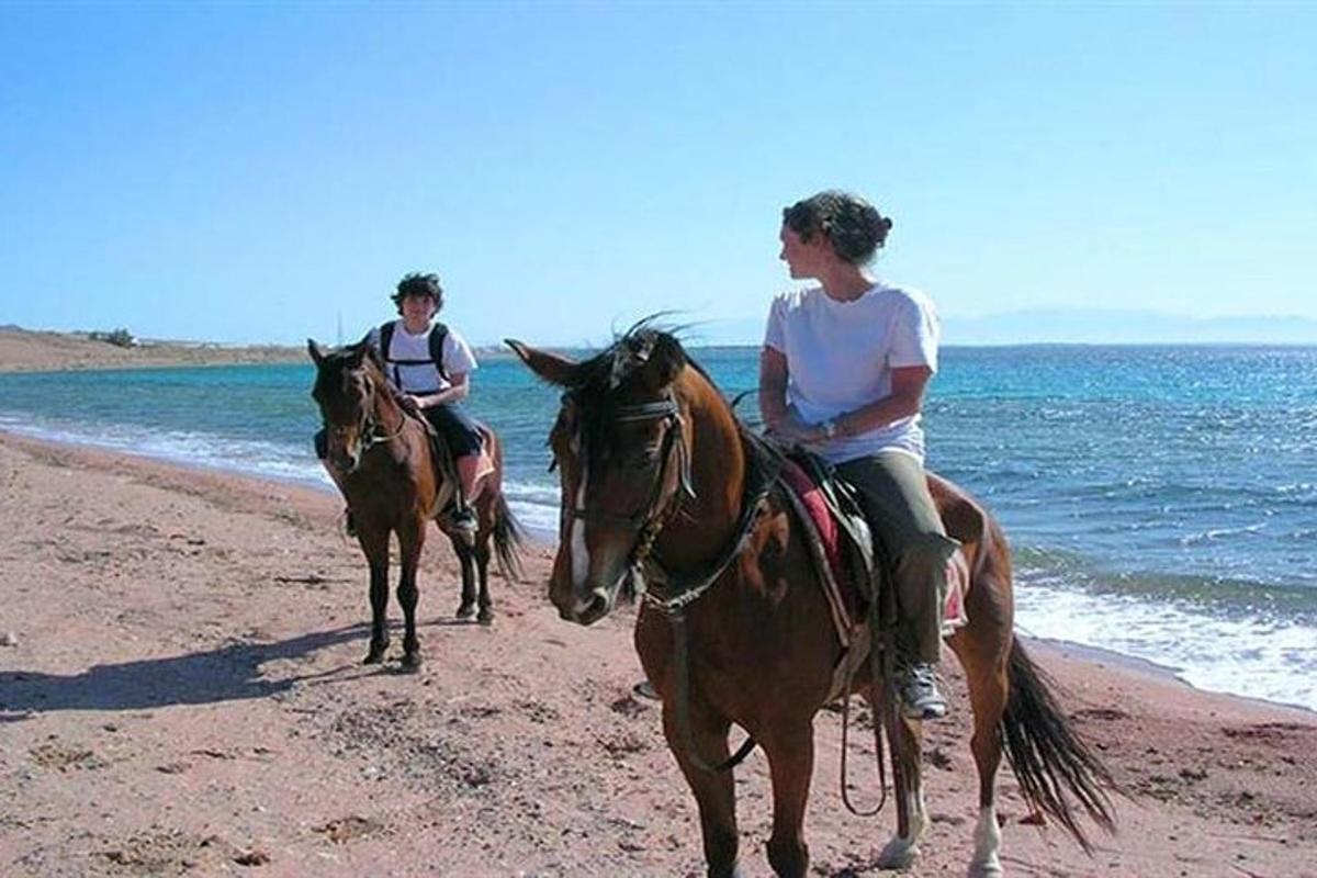 due persone a cavallo sulla spiaggia