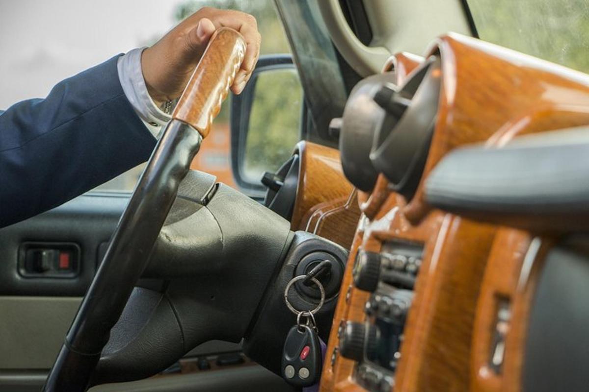 muž řídící auto s dřevěným volantem