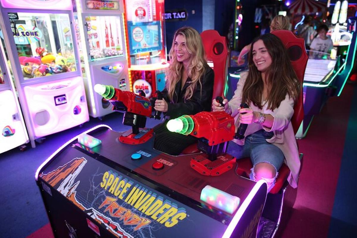 kaks tüdrukut mängivad videomängu pinball-masinal