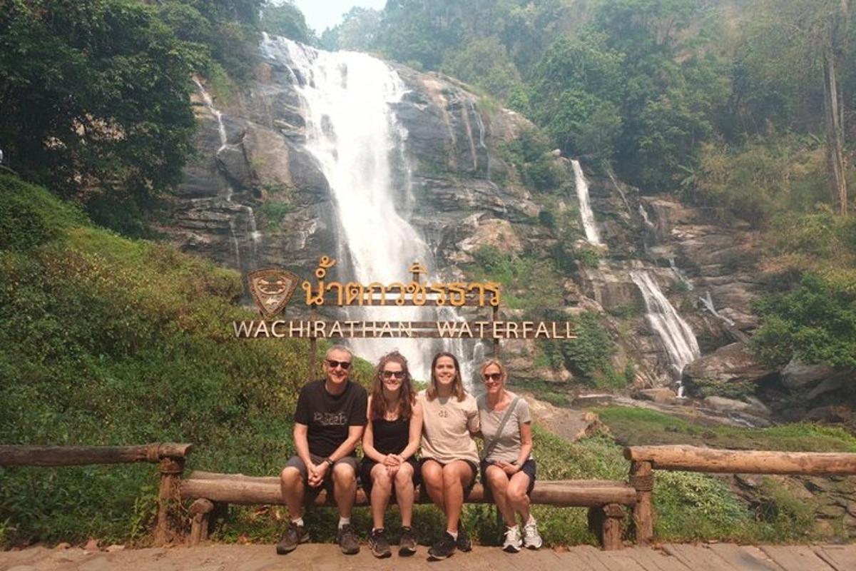 tres persones assegudes en un banc davant d'una cascada