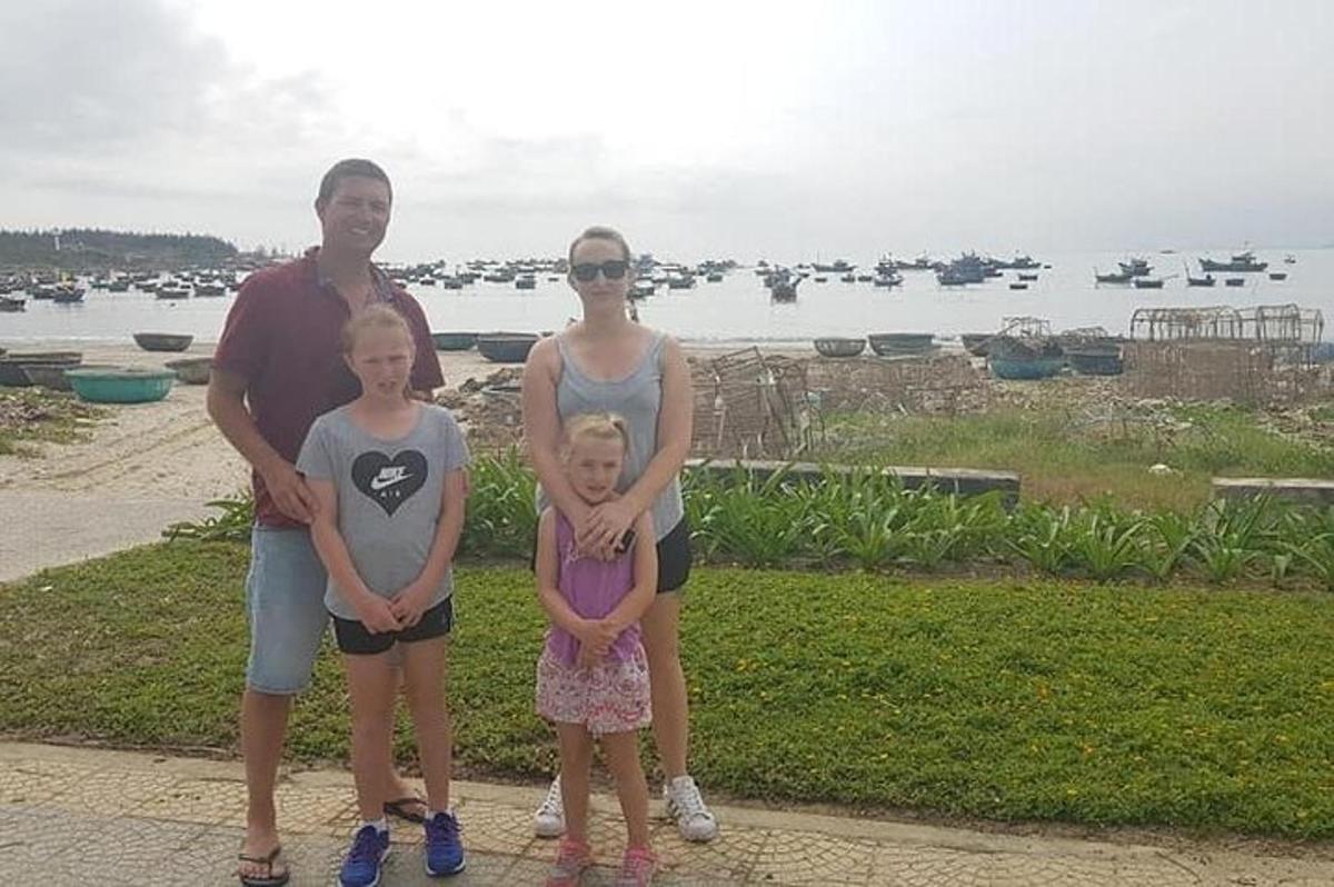 Una familia posando para una foto frente al agua.