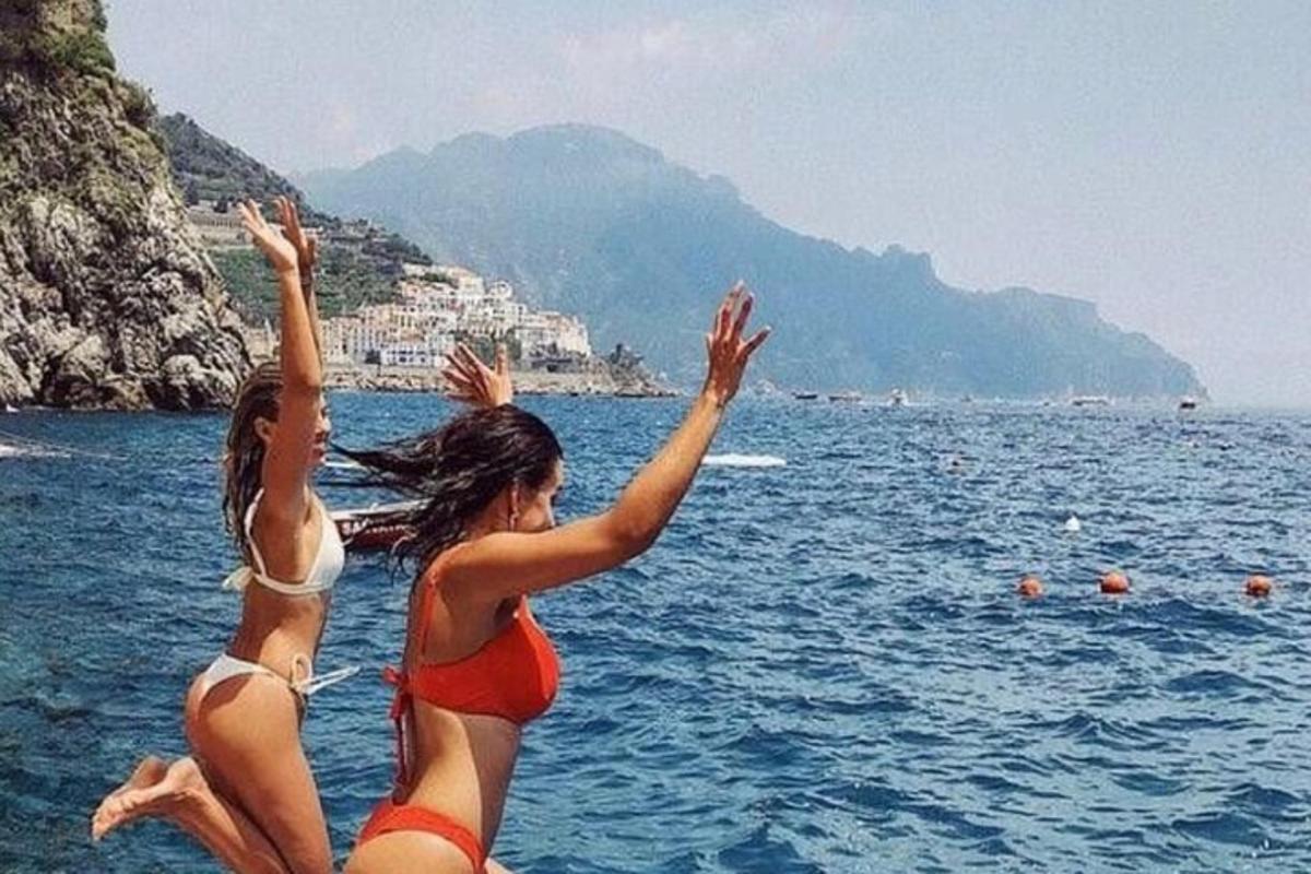 due ragazze che saltano in acqua in spiaggia