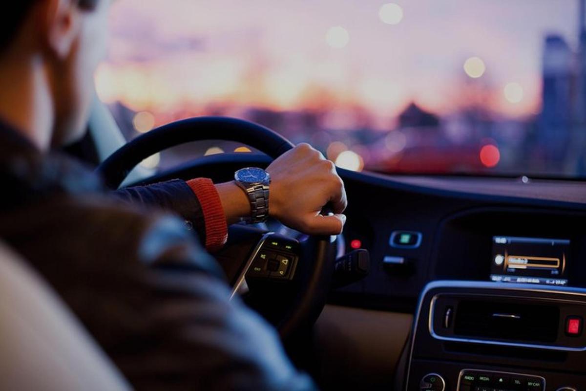 seseorang memandu kereta dengan tangan mereka pada stereng
