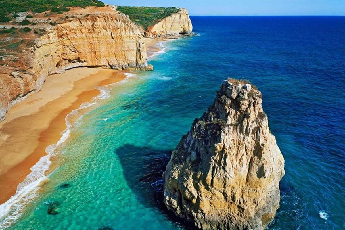 una gran roca a l'oceà al costat d'una platja