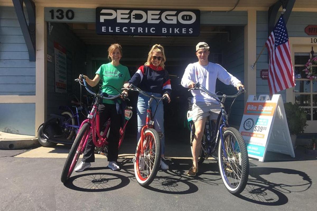 drie mensen poseren met hun fietsen voor een winkel