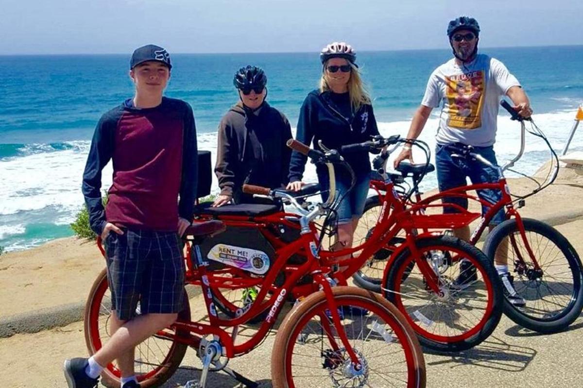 een groep mensen die naast hun fietsen op het strand staan