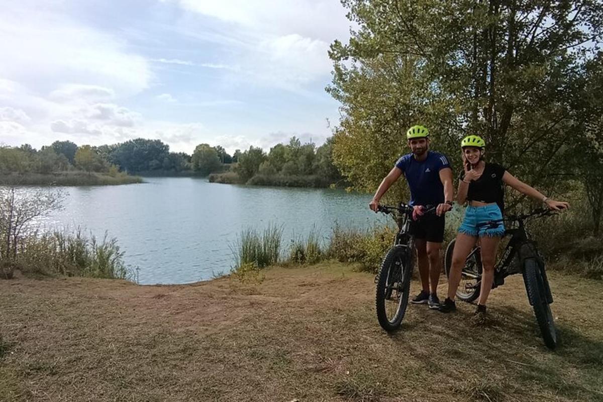dwie osoby stojące ze swoimi rowerami obok jeziora