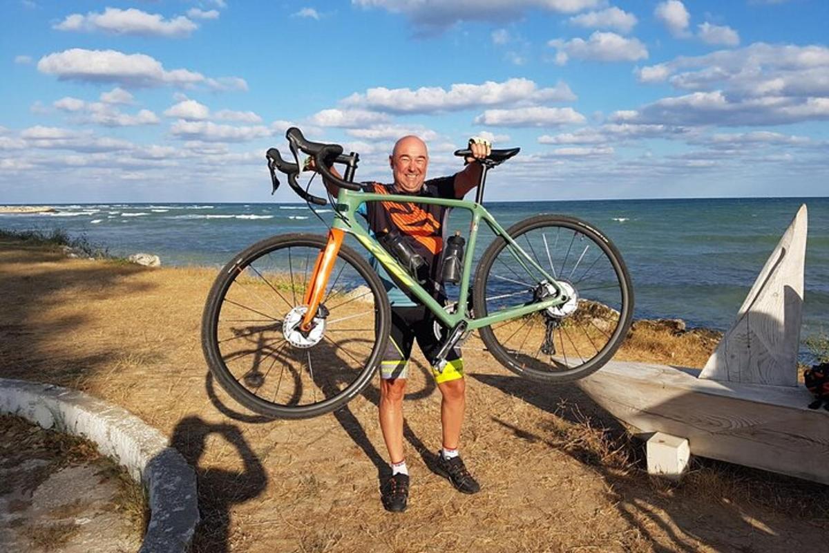 a man is holding a bike on the beach