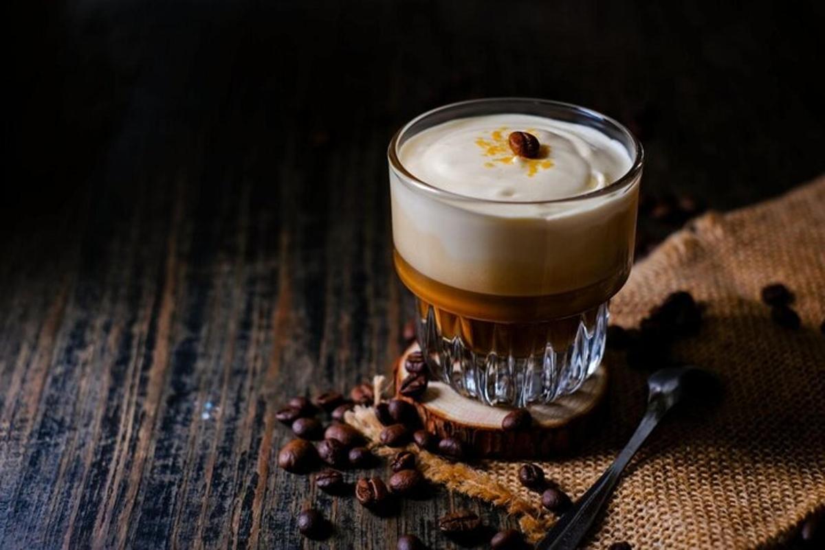 Un vaso de cerveza sobre una mesa con granos de café.
