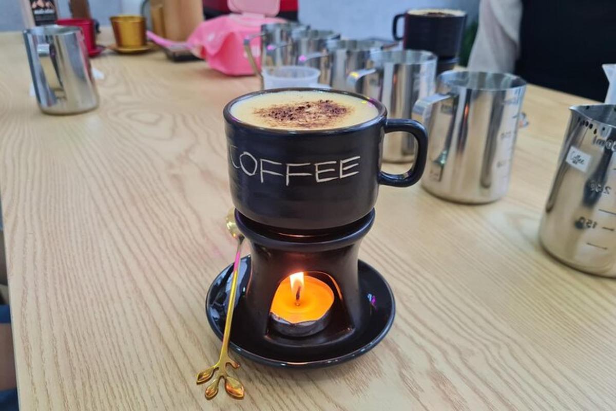 Una taza de café sobre una mesa con una vela dentro.