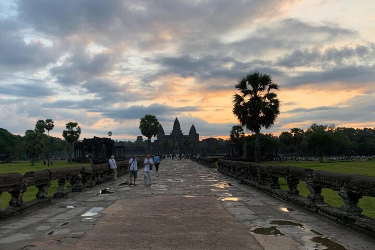 sekumpulan orang berjalan menyusuri laluan batu pada waktu matahari terbenam