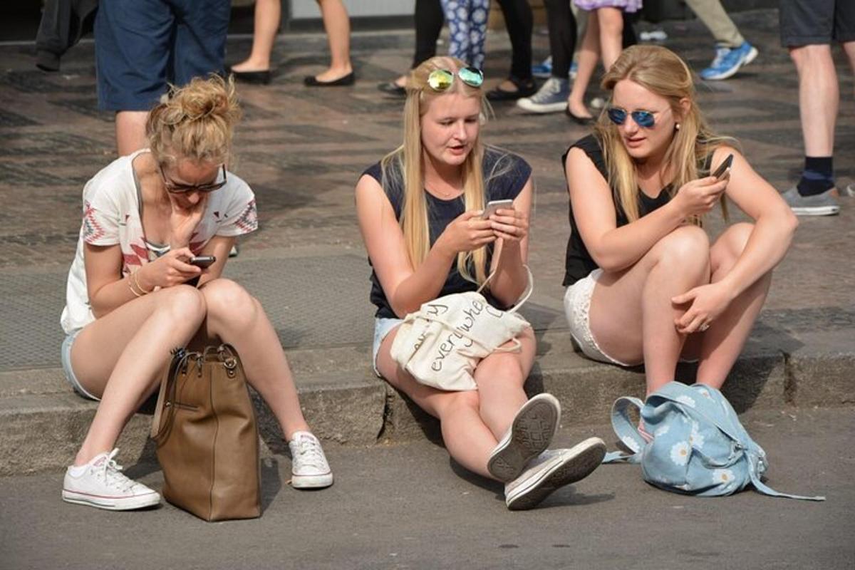 kolm tüdrukut istuvad trepil ja vaatavad oma mobiiltelefone