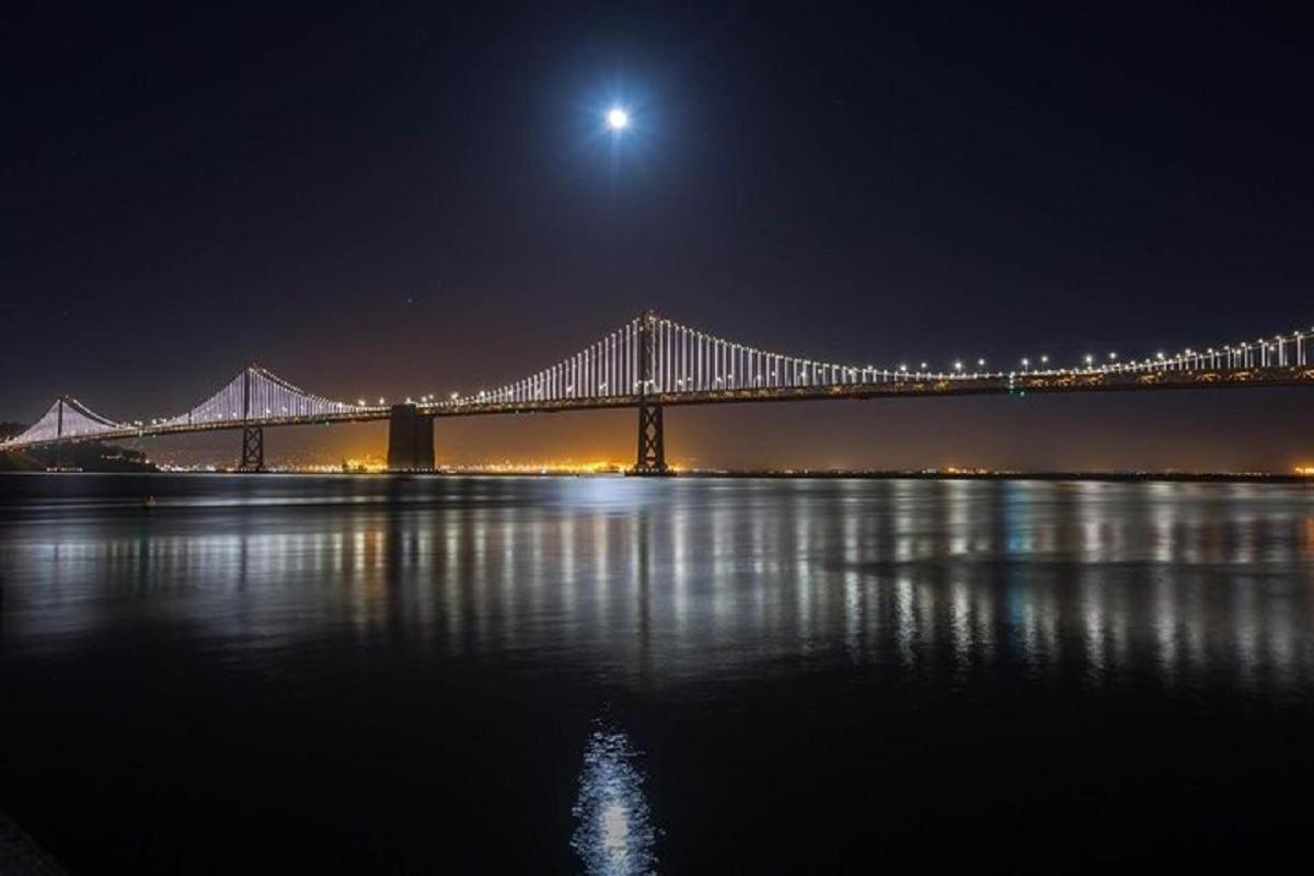 un grande ponte sull'acqua di notte con la luna