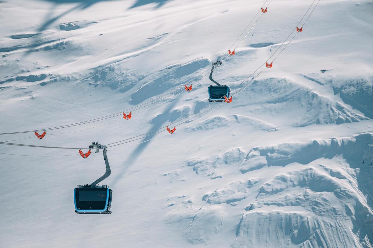 two ski lifts going down a snow covered mountain