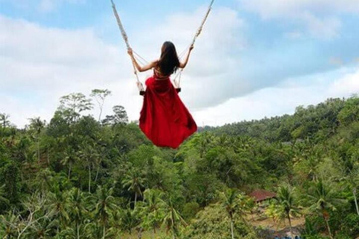 a woman in a red dress swinging on a swing
