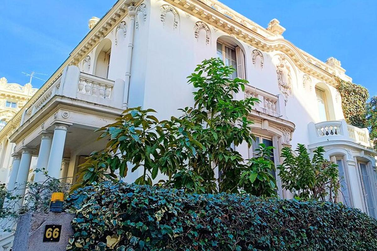 một tòa nhà màu trắng có một cái cây ở phía trước