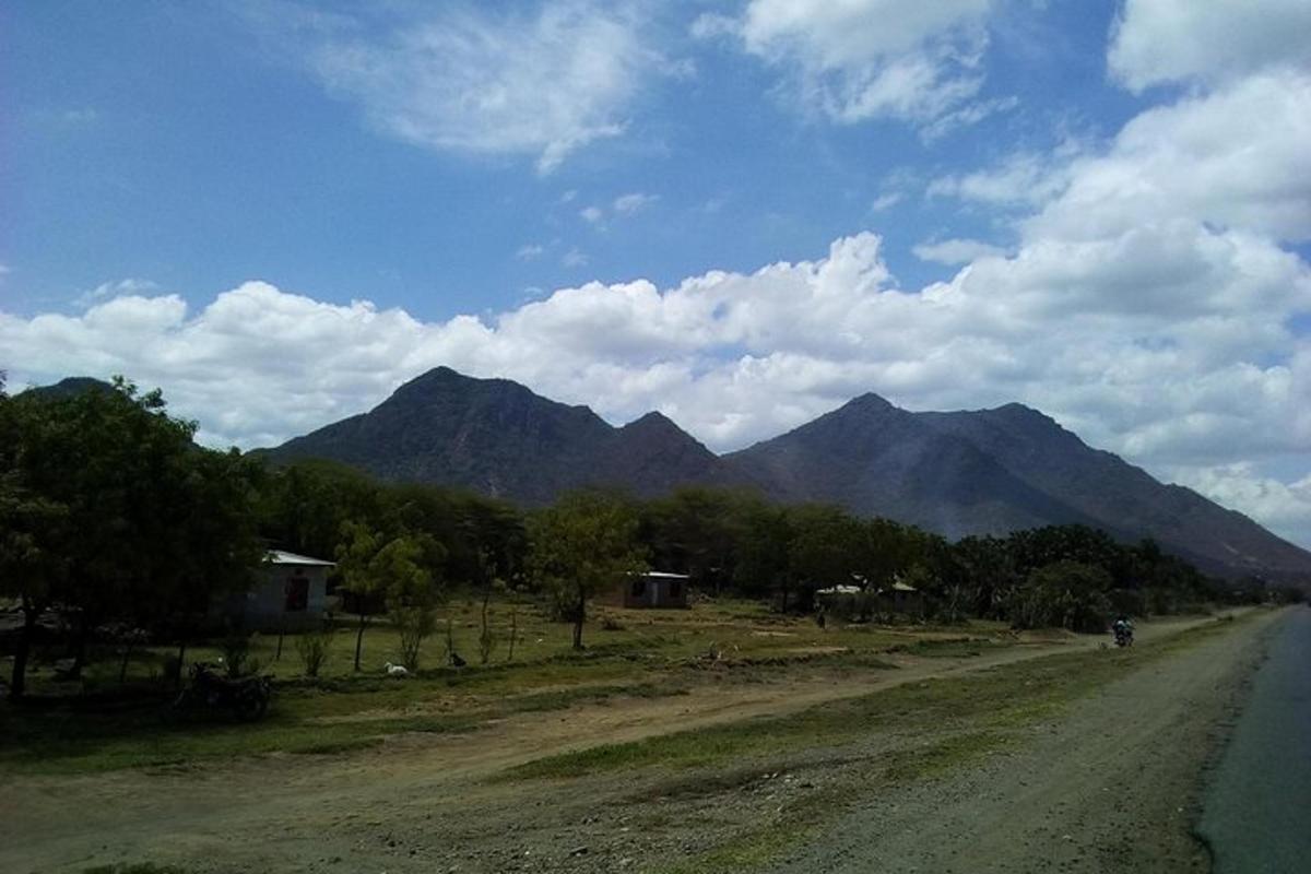 Un camino de tierra con una cadena montañosa al fondo