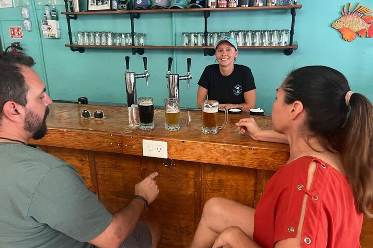 Dos hombres y una mujer sentados en un bar con cervezas