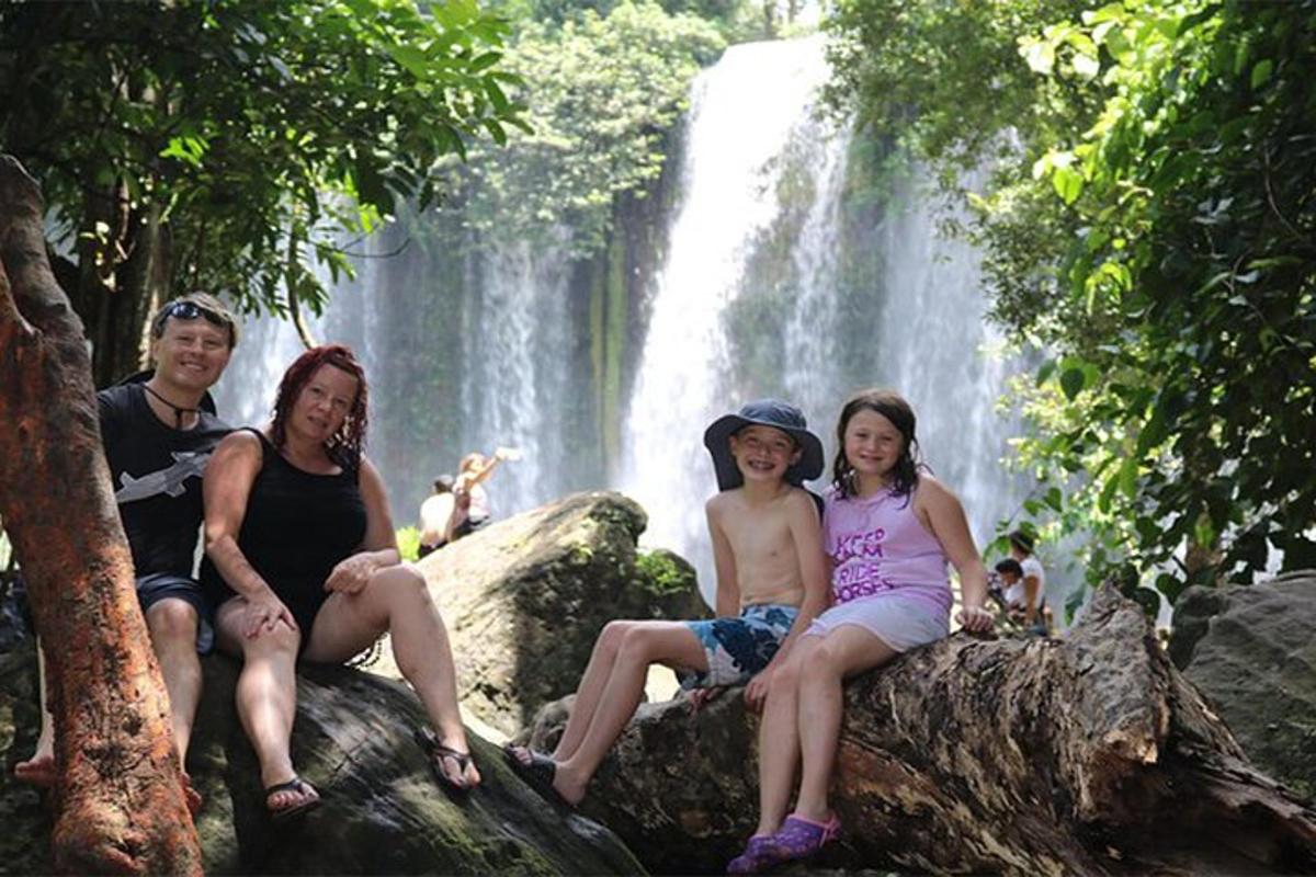 un grup de persones assegudes sobre roques davant d'una cascada