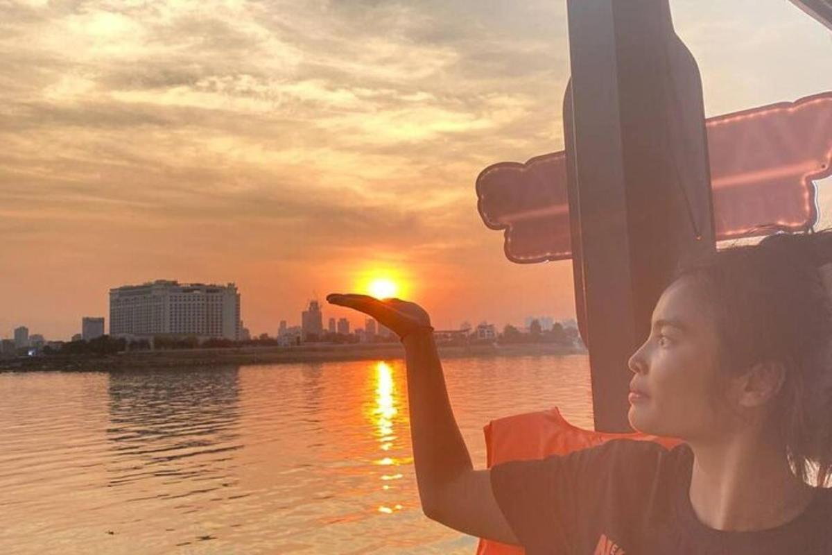 een jonge vrouw kijkt vanaf een boot naar de zonsondergang
