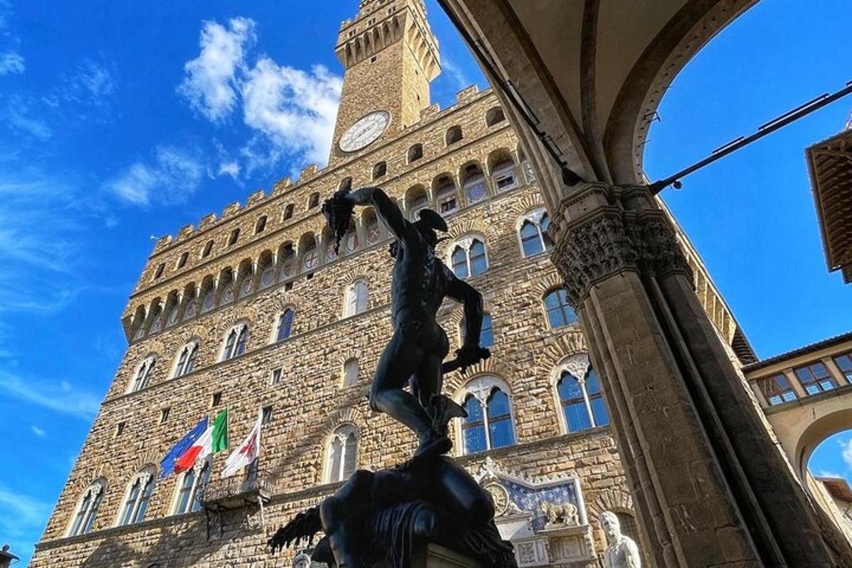 una statua di fronte a un edificio con una torre dell'orologio