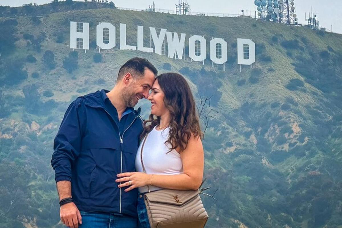 Moški in ženska stojita pred hollywoodskim znakom