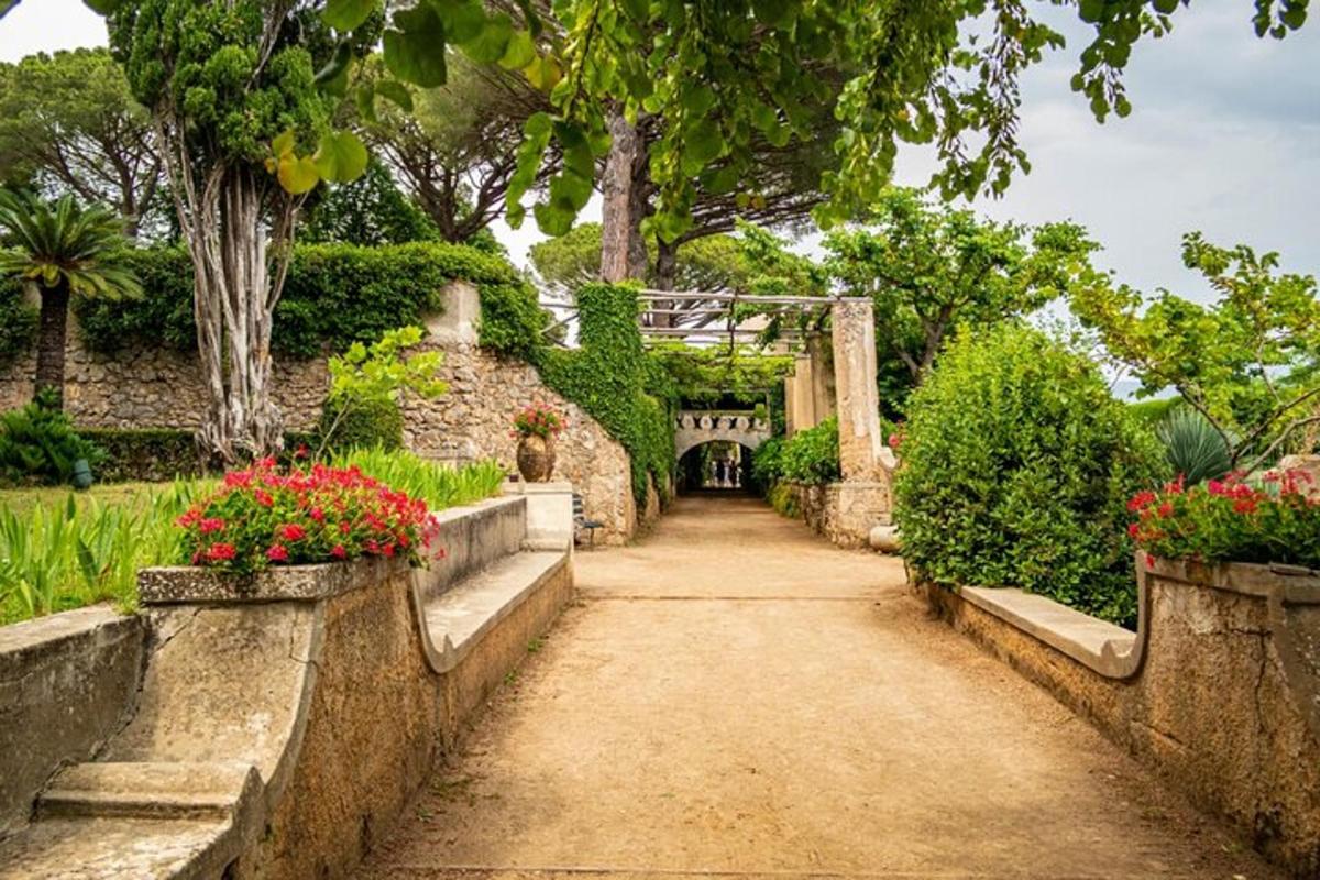 a path in a garden with flowers and a bridge