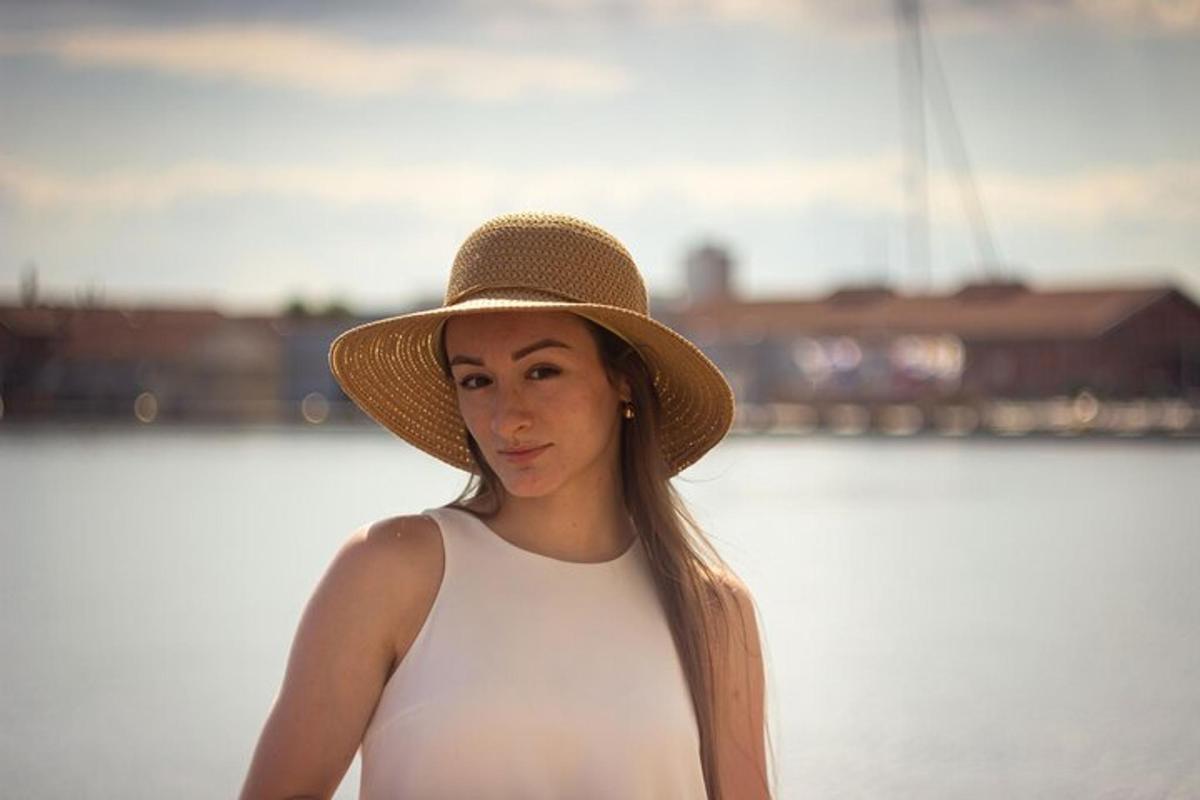 una donna che indossa un cappello in piedi accanto all'acqua