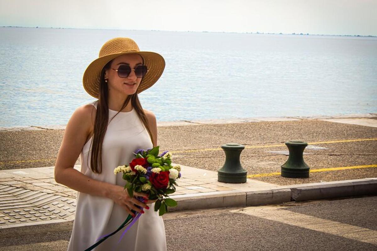 una donna con un cappello che tiene in mano un mazzo di fiori