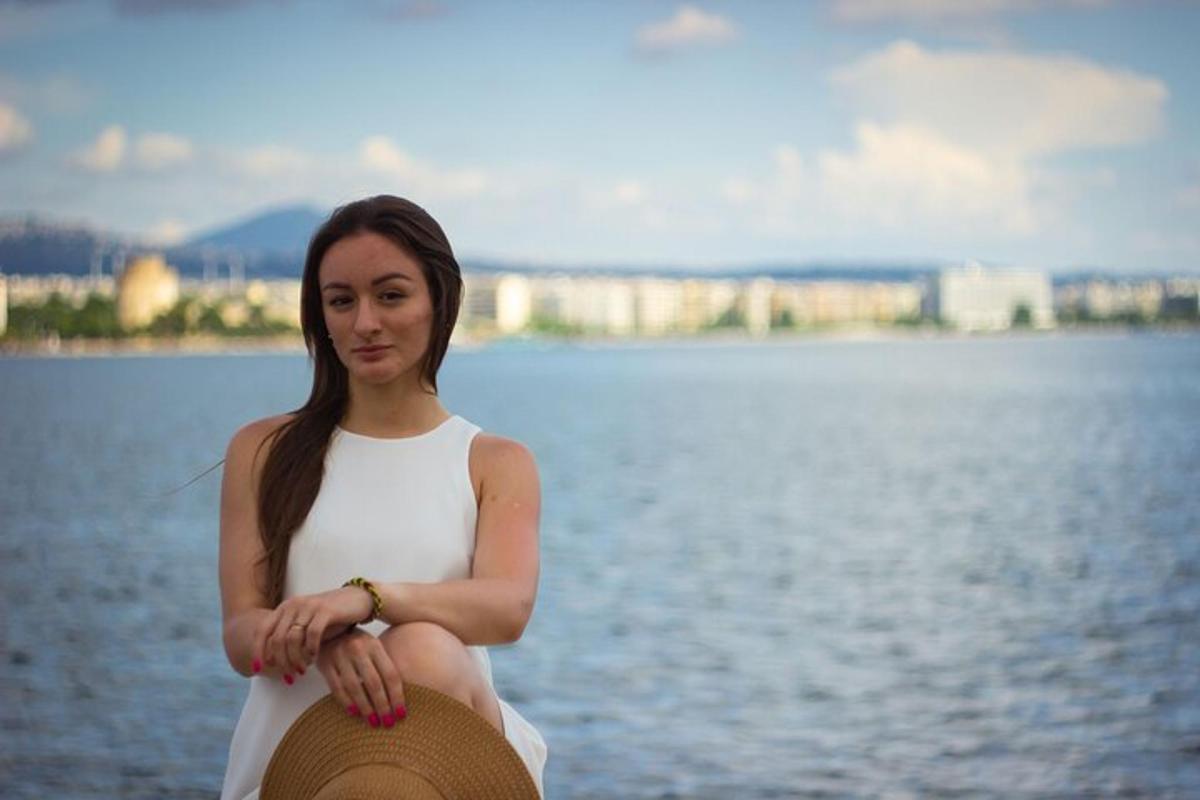 una donna in abito bianco seduta accanto a uno specchio d'acqua