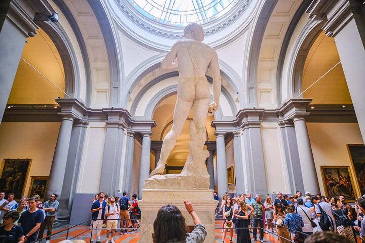 cilvēku pūlis, kas muzejā aplūko statuju