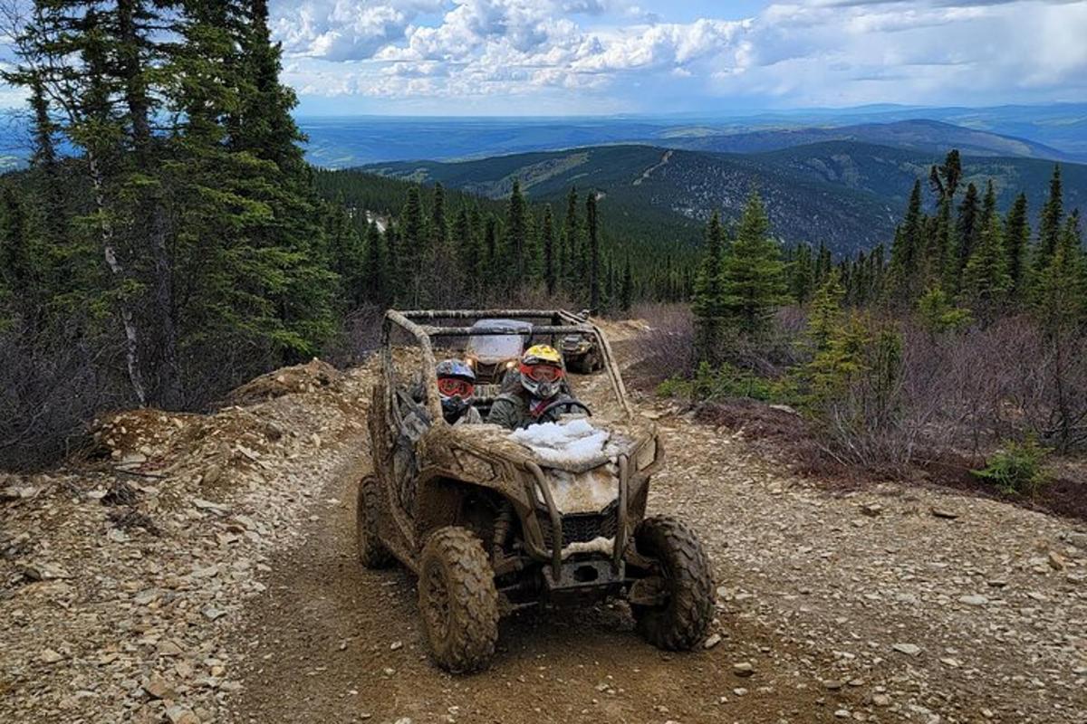 two people riding in a four wheeler on a dirt trail