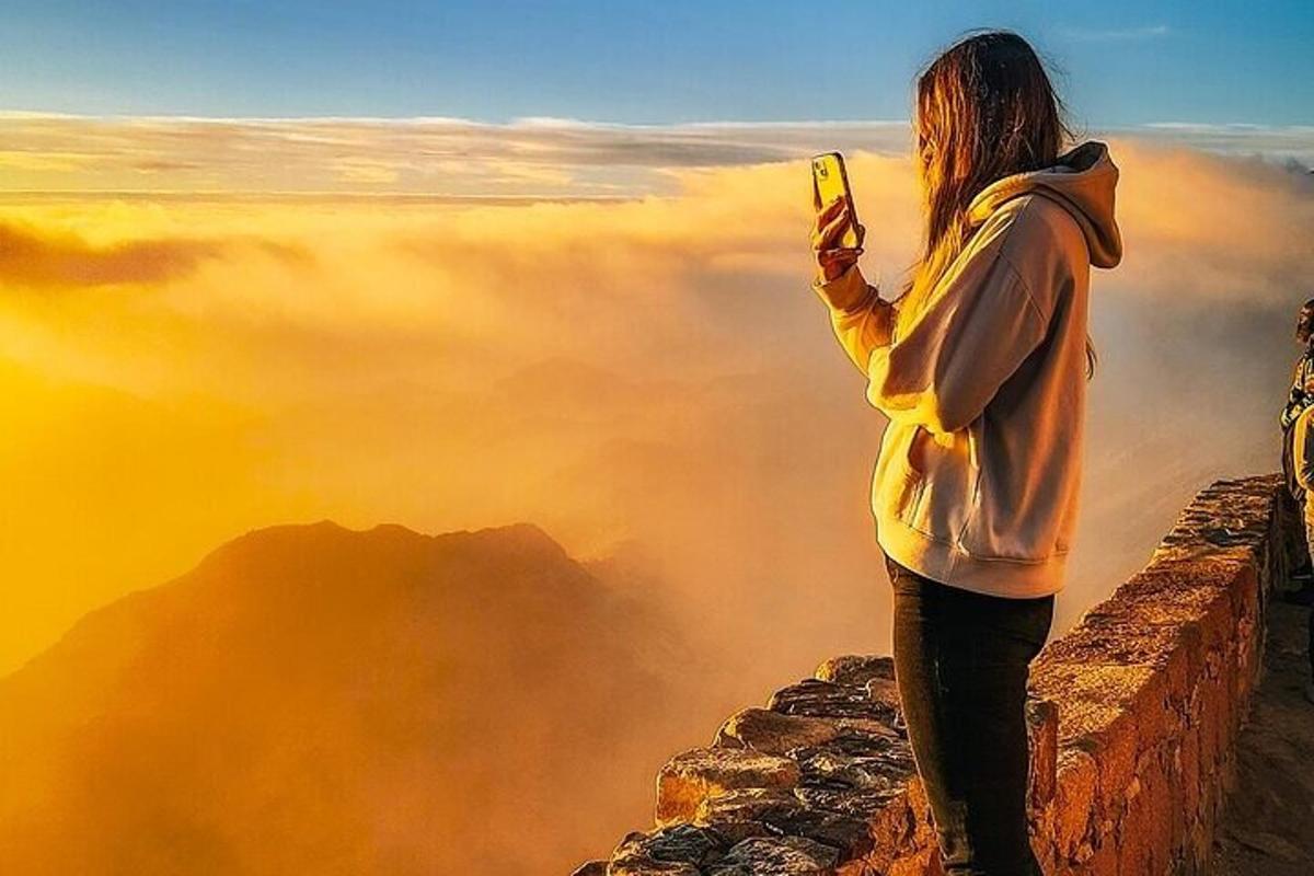 a woman standing on top of a mountain taking a picture