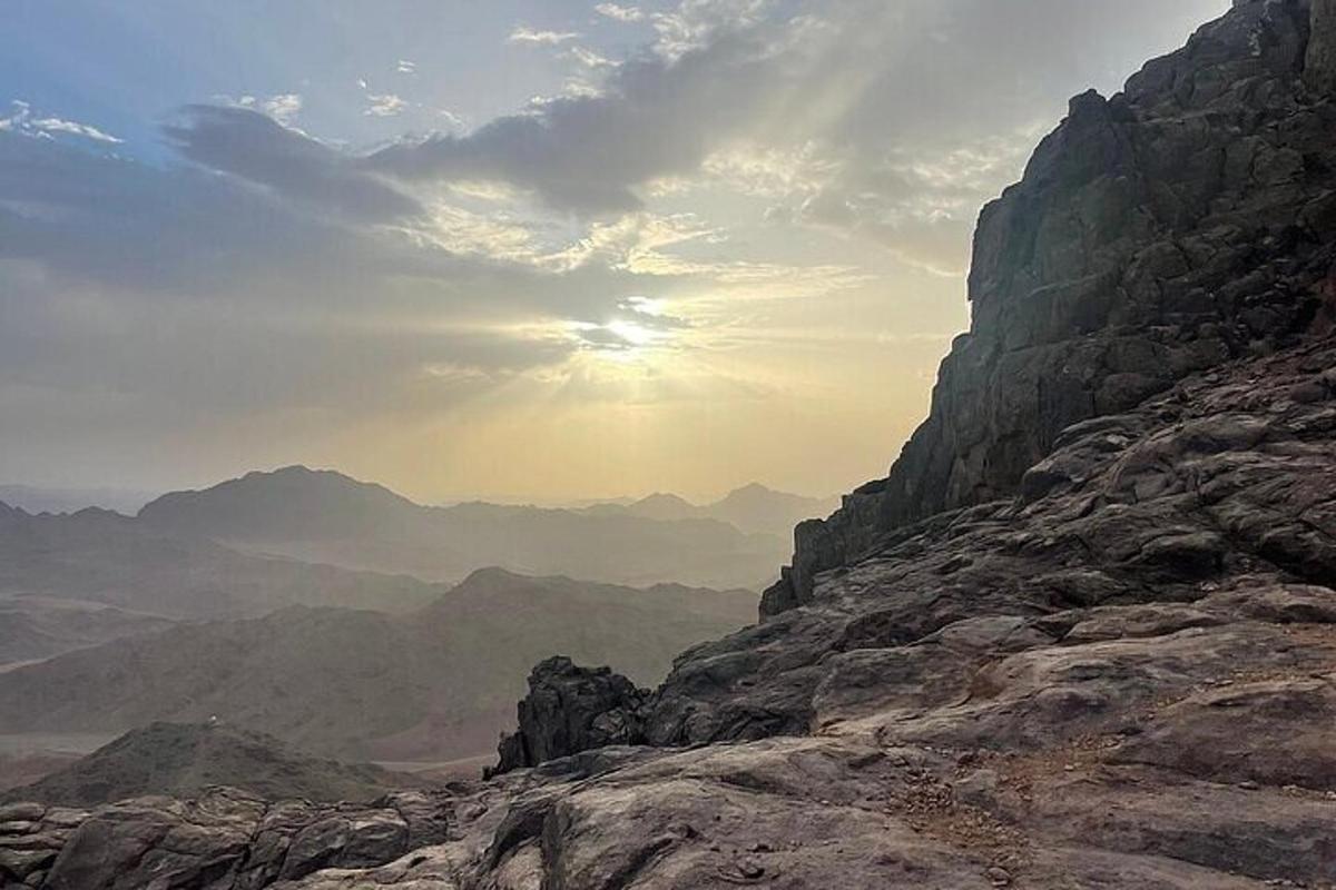 a view of a mountain with the sun in the background