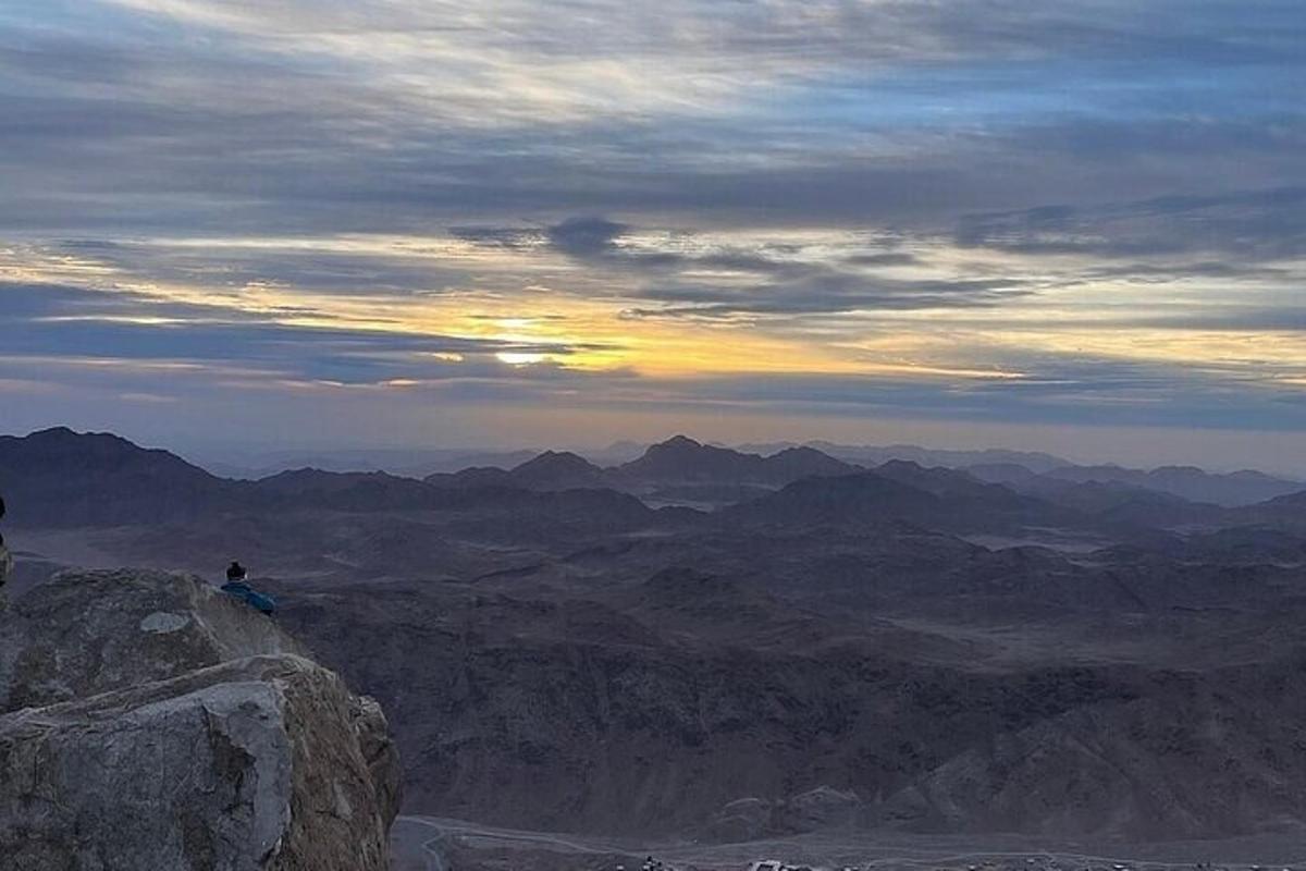 a person sitting on the edge of a mountain at sunset