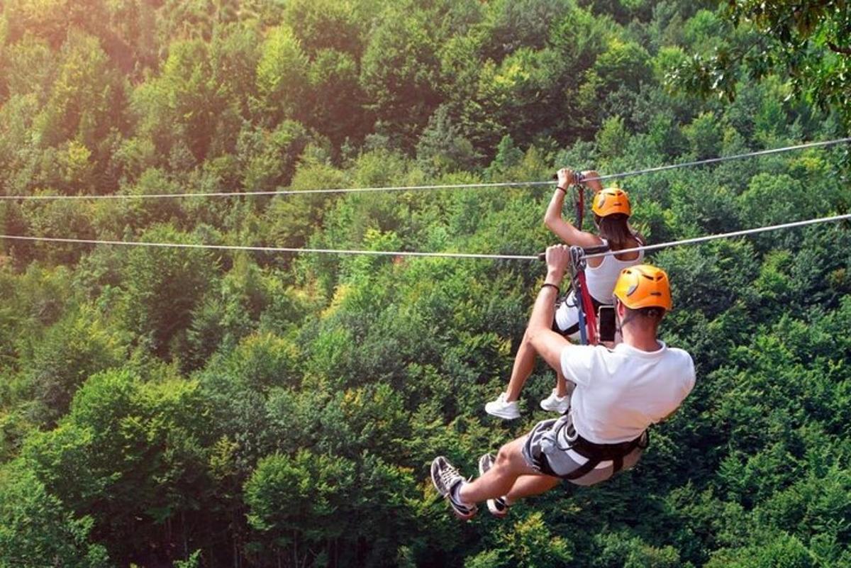 two people on a zip line in the forest