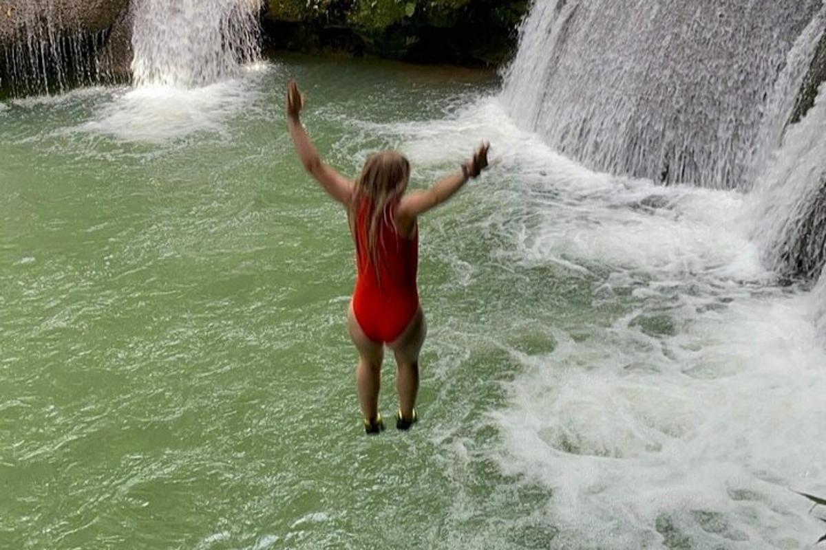 una dona dempeus a l'aigua davant d'una cascada