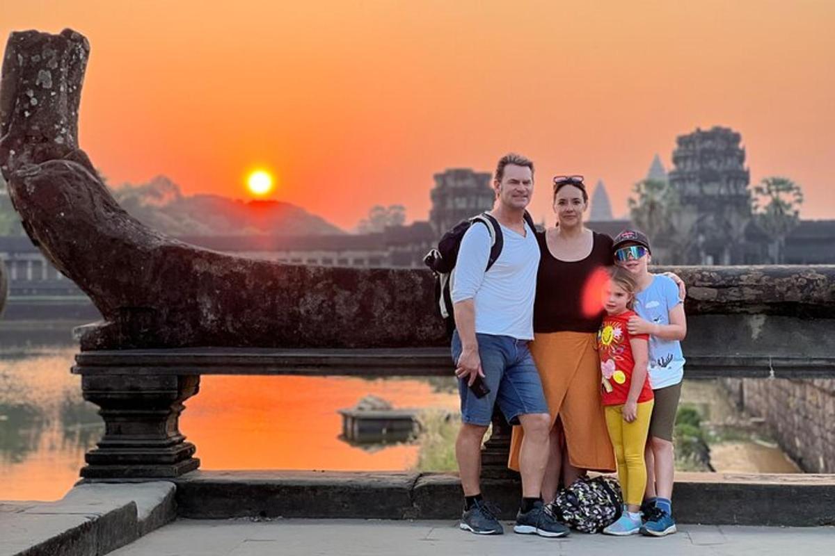eine Familie posiert vor einer Statue mit Sonnenuntergang