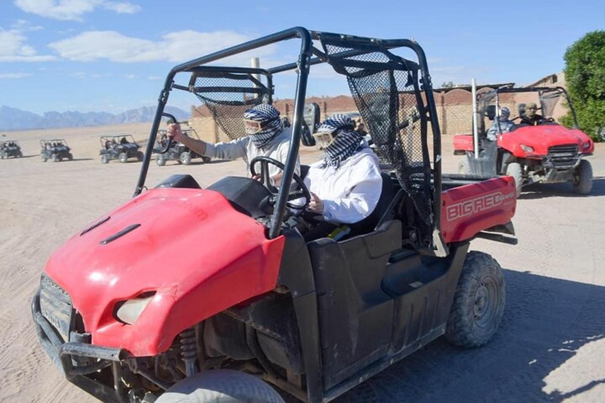 two people riding in a red atv in the desert