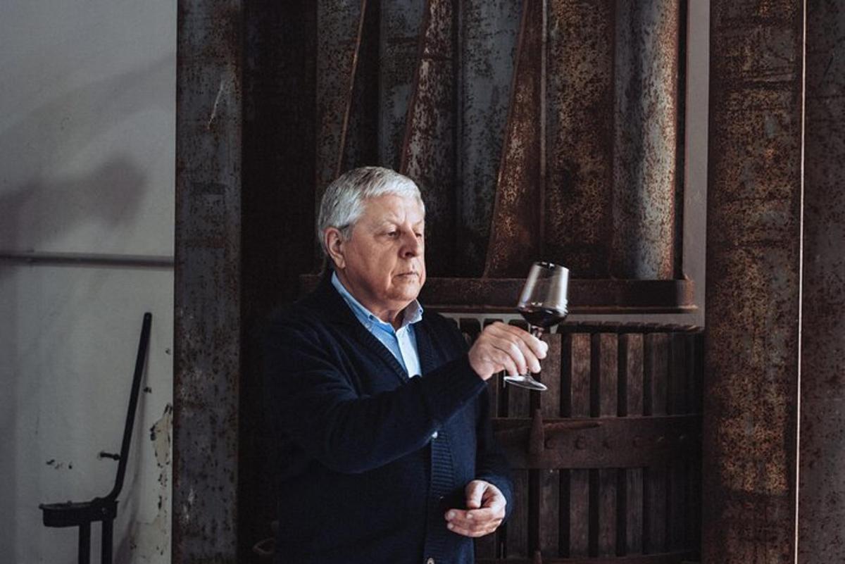 an older man is holding a glass of wine