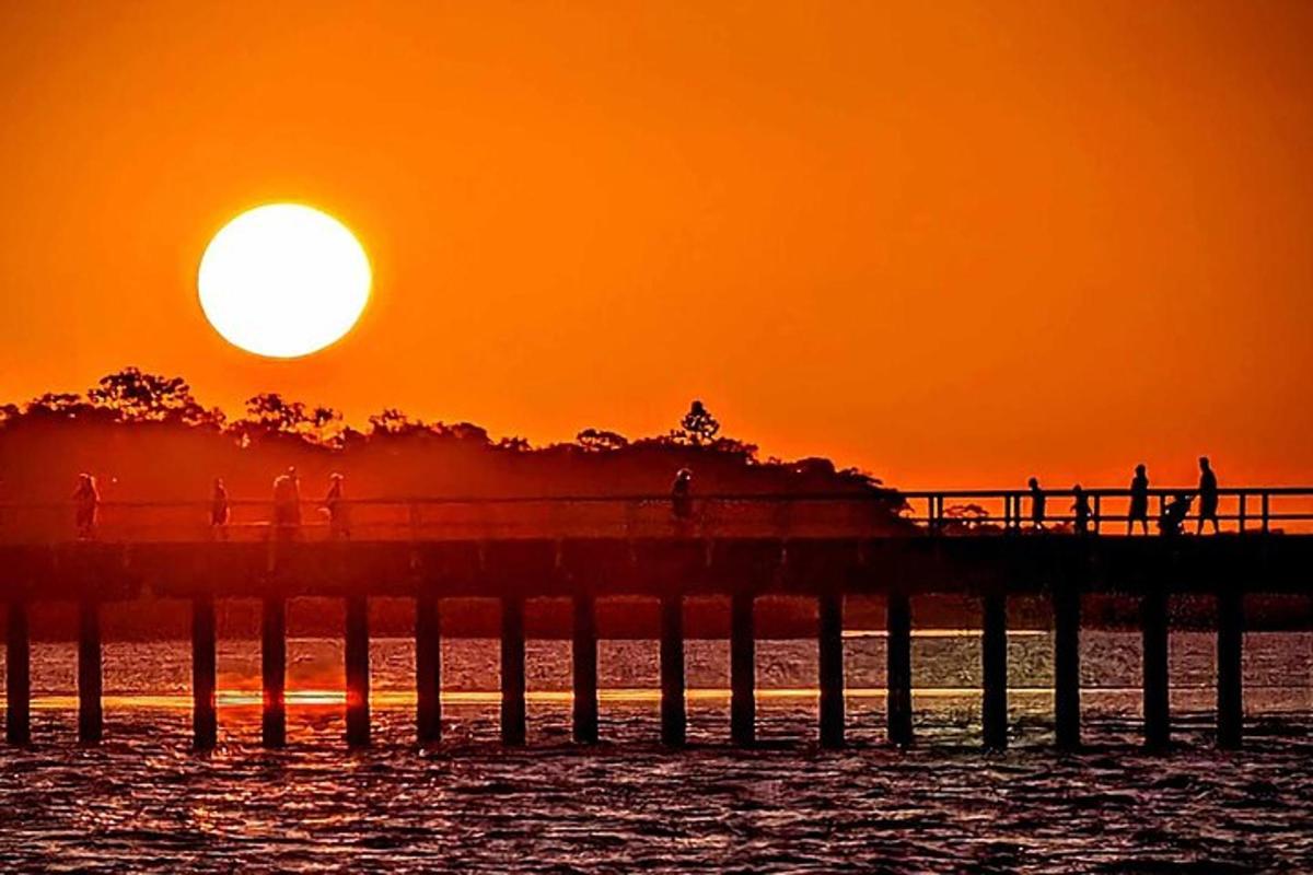 people walking on a pier at sunset