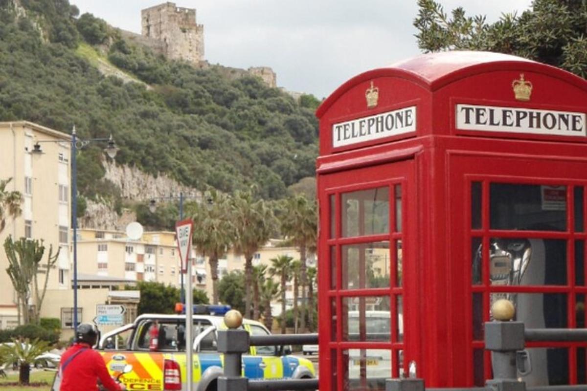 a red phone booth on a street with a castle in the background