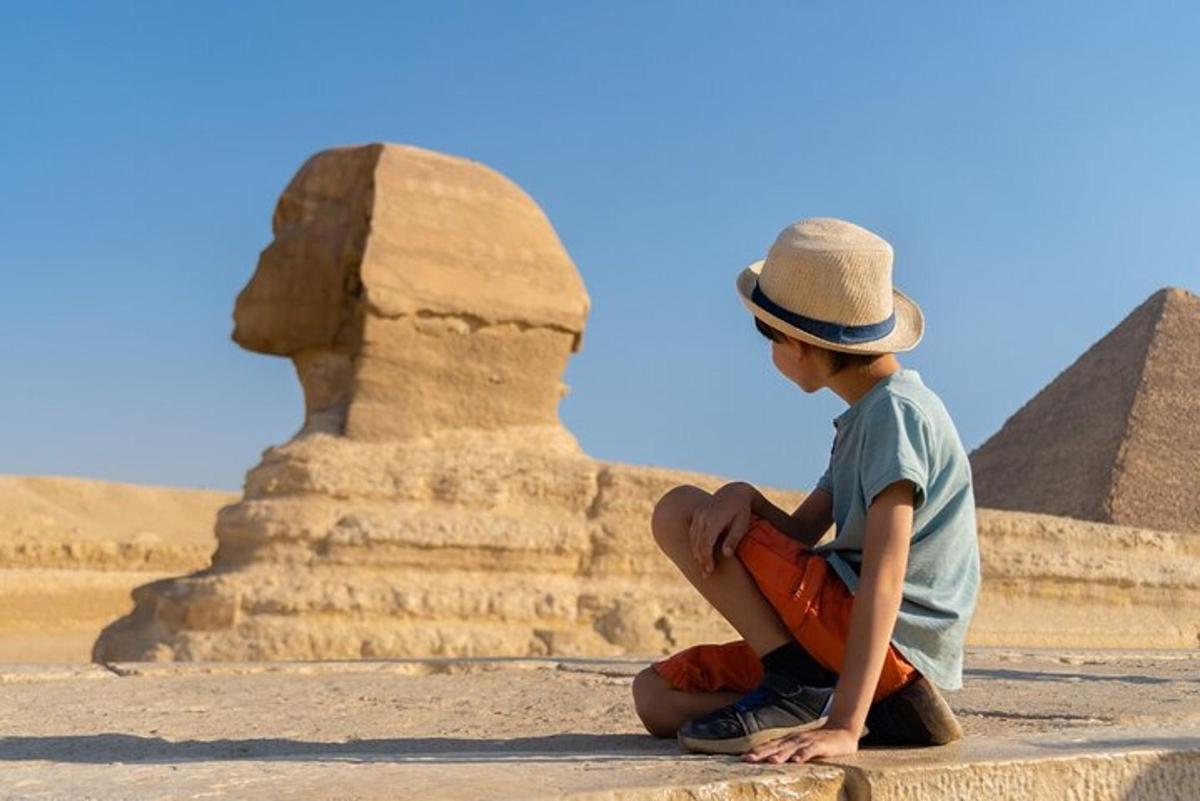 a young boy sitting in front of the pyramids