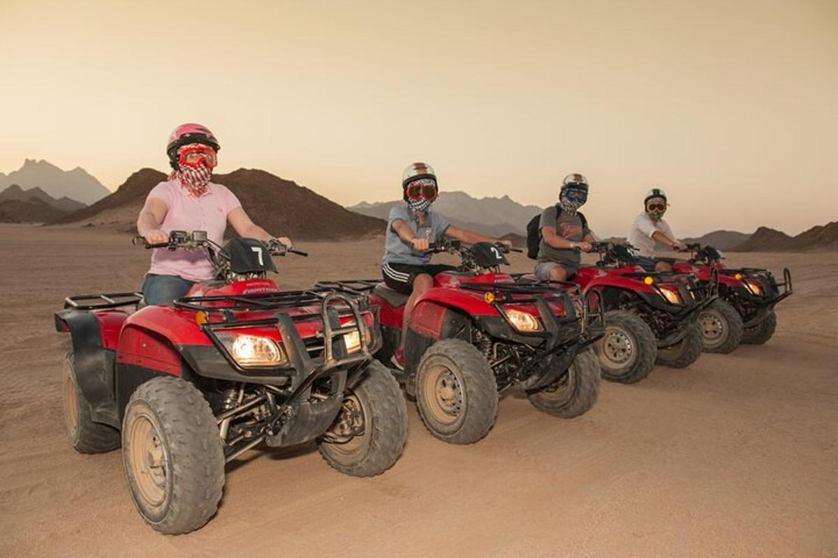 een groep mensen die op quads door de woestijn rijden