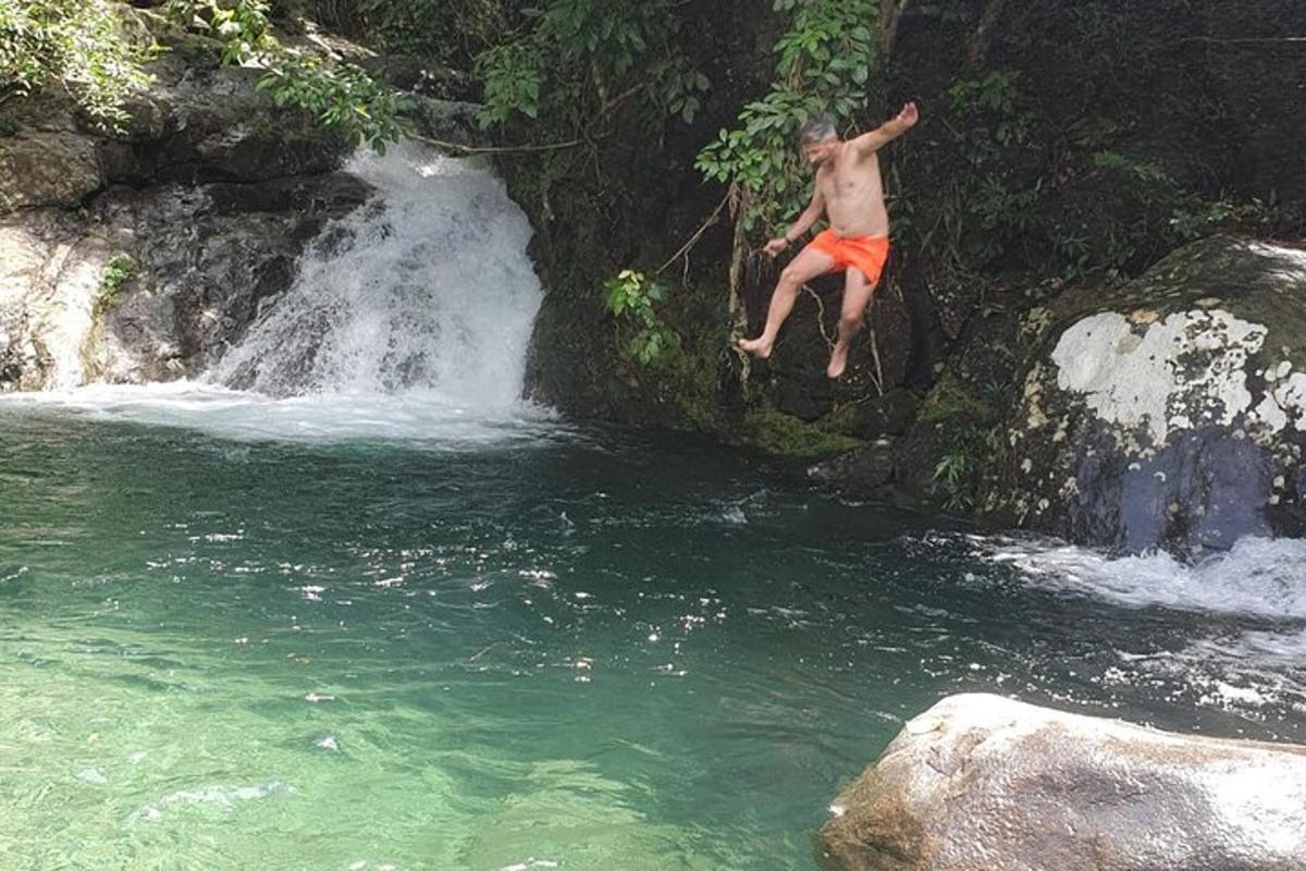um homem pulando de uma cachoeira em um rio