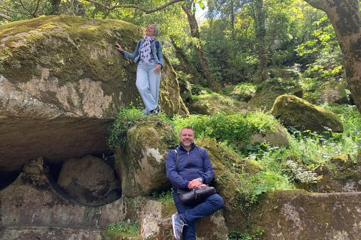 a man sitting on a rock with a woman standing on it