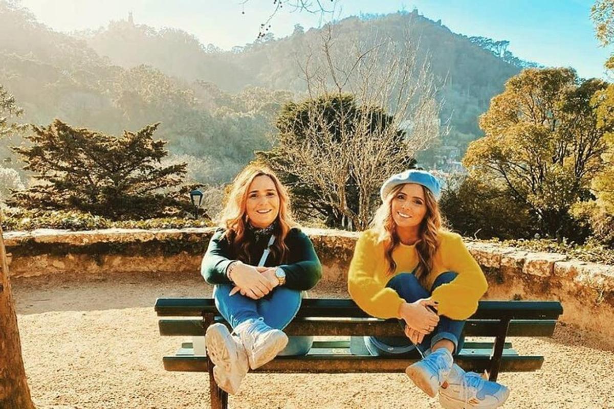 two women sitting on a bench in the mountains
